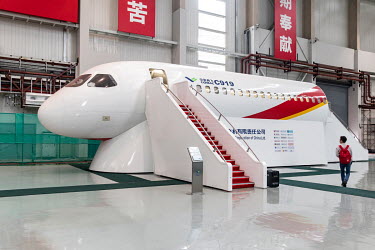 A visitor walks past a mock up of the Commercial Aircraft Corp. of China Ltd. (Comac) C919 aircraft at the Comac Shanghai Research and Development Center.