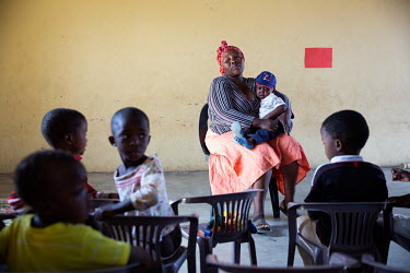 Thulisile Shongwe, a teacher at a community centre (NCP), holds an unset child on her lap while in a classroom.