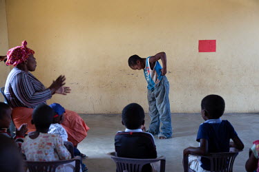Thulisile Shongwe, a teacher at a community centre (NCP) where children receive support and food, claps along as one of her pupils dances during a class.
