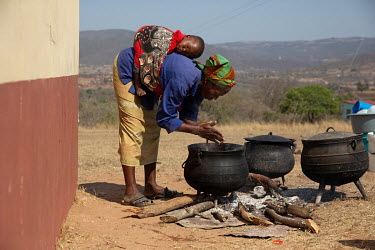 Nompumelelo Zinisa, her baby Bapelele sleeping strapped on her back, prepares food which is given free to children attending the community centre (NCP) school.