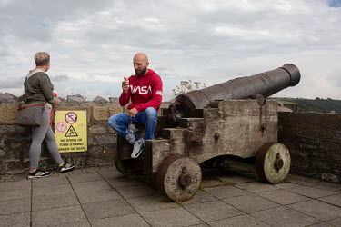 A man sits on a canon on the city wall eating and ice cream as tourists return to the Harbour and the Hoe as Plymouth begins to reopen following the easing of the first coronavirus lockdown.