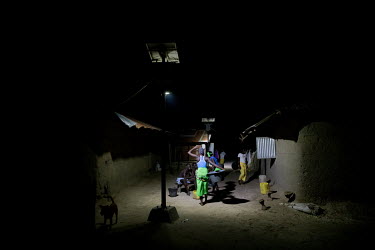 Villagers socialise under bright lights after dark following the installation of a solar power grid paid for by the community which supplies street lighting and, for a monthly subscription, electricit...