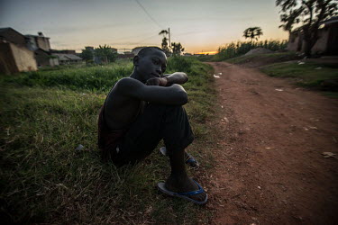 A boy sits beside a path outside the RHU clinic at sunset.