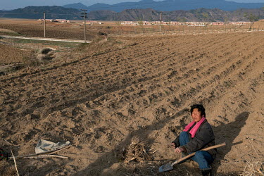 A farmer working in a ploughed field that is ready for planting.