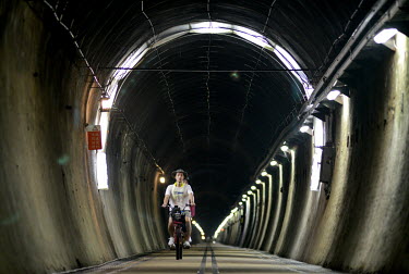 A couple cycling through the 2.1KM Old Caoling Railway Tunnel pass the subterranean border of New Taipei City with Yilan County. Domestic tourism is booming across Taiwan where a combination of almost...