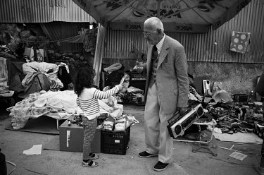 A child offers a packet of crips to an old man at Sunday flee market.
