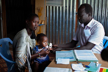 William Diang, Assistant Programme officer at Concern Worldwide and a trained nurse, carries out an MUAC test (mid-upper arm circumference) on a young girl while working at a nutrition clinic in Prote...