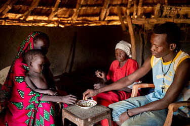 Agol Agnot (25) and her husband, Ariath (24) eating peanuts with grandmother, Achol Akech (60), at their home in Majook village. The couple have three children Amin (7), Deng (5) and Nyigeng (2 Â�) w...