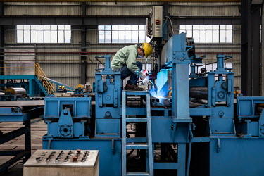 A worker welding steel sheets in the metal pressing shop at the Singamas Container Holdings factory. As part of their pledge to cut emissions by 70 percent by the end of 2017, and in response to the C...