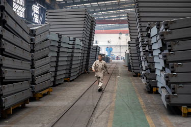 A worker walks by end frames used for making shipping containers at the Singamas Container Holdings factory. As part of their pledge to cut emissions by 70 percent by the end of 2017, and in response...