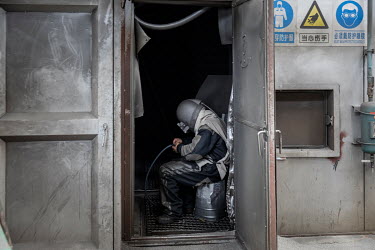 A worker, wearing protective clothing, sits in a sand blasting chamber at the Singamas Container Holdings factory. As part of their pledge to cut emissions by 70 percent by the end of 2017, and in res...