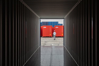 A worker walking past shipping containers at the Singamas Container Holdings factory. As part of their pledge to cut emissions by 70 percent by the end of 2017, and in response to the Chinese governme...