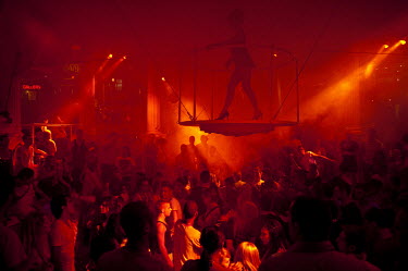 A crowd stands beneath a woman dancing on a suspended podium at Es Paradis discotheque in San Antonio.