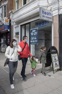 A family walk past a dry cleaning store in Hampstead, a business that has closed down as the British economy sinks into recession due to the coronavirus pandemic.