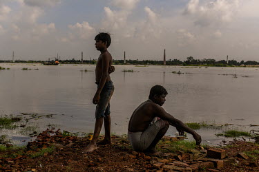 Suman Das (13) waits with his father Bapi Das on the banks of Ichamati River in North 24 Parganas. Suman used to makes bricks in a factory after school, but now he has left school since the coronaviru...