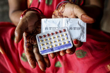 Local health care advisor, Bosundhara Gaire (35), holds a blister pack of contraceptive pills and a packet of condoms.