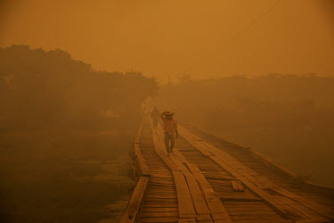 Volunteers cross a wooden bridge on the Transpantaneira highway that they are monitoring during a wildfire endangering the structure in the Pantanal.  Since the beginning of 2020, the Pantanal has b...