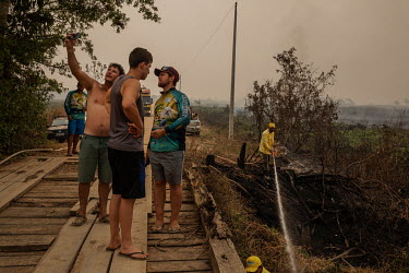 Tourists take selfies while members of the fire brigade put out a spot fire burning a wooden bridge on the Transpantaneira road in the Pantanal.  Since the beginning of 2020, the Pantanal has been f...