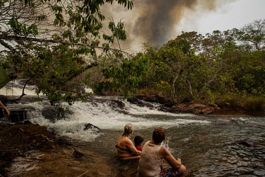 A group of tourists, bathing in the waters of the Mutum River in the rural Santo Antonio Leverger, watch smoke rising from one of the many wild fires burning in the Pantanal.  Since the beginning of...