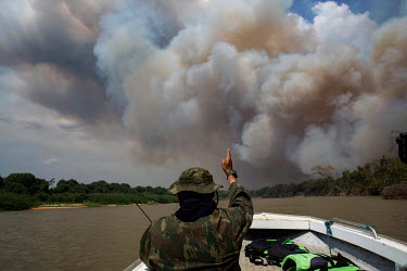 A member of the military directs a boat in the direction of a fire that has broken out on the banks of the Cuiaba River in the Pantanal.   Without a coordinated firefighting action by the federal go...