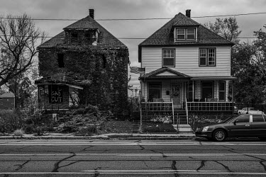 An abandoned and decaying house stands beside one in good repair..