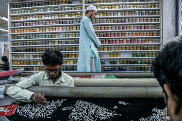 A labourer stops work to offer the Namaz prayer while his colleagues continue their work attaching beads and sequins to fabrics in a factory in Lower Parel that is part of Maximiliano Modesti's Les At...