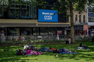 People sleep rough in Leicester Square where a closed cinema displays 'thank you NHS' on a giant digital screen.