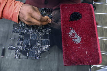 A labourer at an embroidery subcontractors attaches sequins and beads to a fabric in a small factory housed in a residential block. The factory does not adhere to the Indian government's Factory Act o...