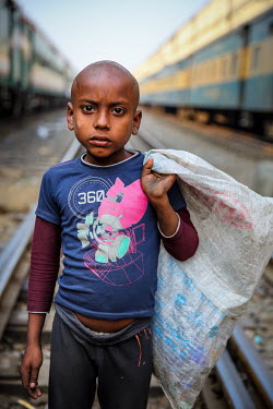 A homeless boy collects rubbish for recycling at a railway station
