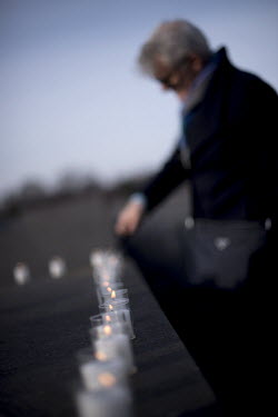 A woman lights a candle during a ceremony to commemorate the victims of the Holocaust at the Holocaust Memorial (Memorial to the Murdered Jews of Europe) on the 75th anniversary of the liberation of t...