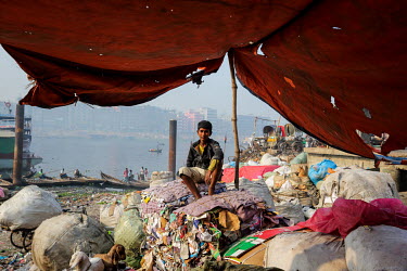 A homeless boy sits on piles of recycling stored by the Buriganga River.  It is estimated that there are more than 600,000 street children living in Bangladesh, 75% of them live in the nation's capita...