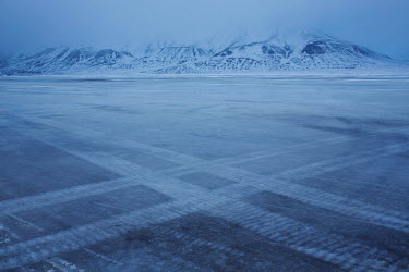 Tracks on the frozen fjord from crawler trucks that take tourists to see the region around Longyearbyen, the northernmost city on the planet. Temperatures in this region are warming faster than anywhe...