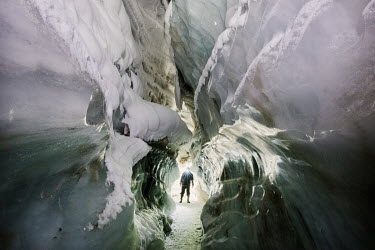 A person in an ice cave which has grown in size as a result of higher temperatures melting the Longyearbreen glacier. Temperatures in this region are warming faster than anywhere else on the planet, r...