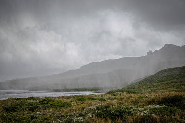 A rain front, coming from the south, towards the expedition campsite on Cape Horn Island (Isla Hornos). The peak in the background is Cape Horn, it marks the northern boundary of the Drake Passage and...