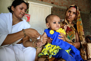 A health worker gives a baby an injected vaccination during during a village health and nutrition day.