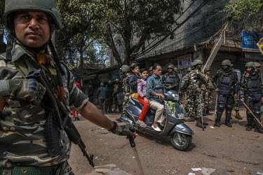 A family ride a motor scooter past armed security personal following rioting. When rival groups, largely split between Hindus and Muslims, began protesting for and against the new Citizenship Amendmen...