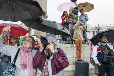 Catholic pilgrims listen in the rain to Pope Francis speaking from the window of his apartment on Saint Peter's Square in the Vatican City. Each Sunday around noon, the Pope gives a short speech follo...