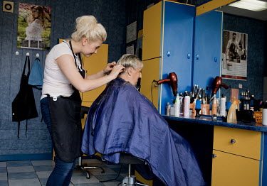 A hairdresser cutting a woman's hair in a salon.