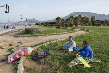 Two Bangladeshi migrants sell toys, balls and kites in the Foro Italico recreation area on the Mediterranean seafront.