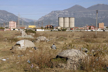 A man sits on the ground between communist-era concrete bunkers and rubbish on the desolate outskirts of the city.