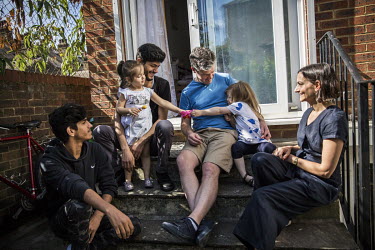 The daugthers of Mohamed Al-Shaabin and James Lynch play together while Islam (left) and Claire Tillotson look on, at the Al-Shaabin home in south London. James and Claire are members of Peckham Spons...