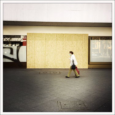A woman walks past a closed and boarded up shop on the Kurfuerstendamm.  The Berliner Ku'damm is lined with luxury boutiques, hotels and restaurants. The coronavirus has resulted in deserted pavements...