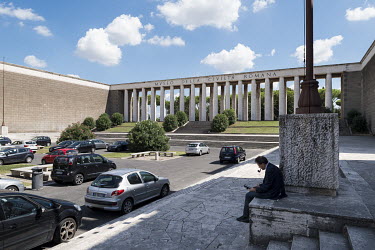 A man smoking a pipe outside the Museo Della Civilta Romana or Roman Culture Museum in EUR, a residential and business district in Rome. This area was originally chosen in 1930s as the site for the 19...