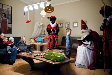 Saint Nicholas or Sinterklaas (Santa Claus) with Swartz Piet blackface characters delivering presents to children.