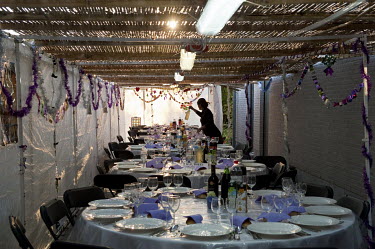 A woman lays tables for a Sukkot meal.