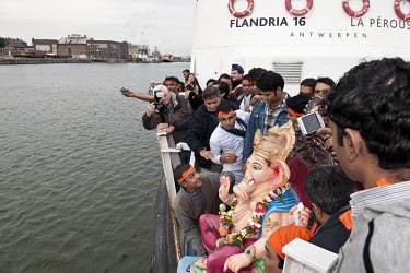 Members of the Indian Hindu community celebrating Ganesh Chaturthi prepare to throw a plaster statue of Ganesha into the Schelde River following a procession to the water's edge.