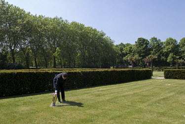 A man spreads of the ashes of a cremated person on a lawn.
