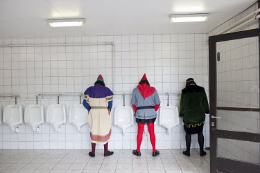 Three men wearing medieval costumes use urinals before participating in the Ros Beiaard procession.