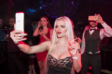 A woman filming with a mobile phone in a nightclub on New Year's Eve.