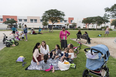 A Sri Lankan maid looks on as a family of expats gather in the evening on a park within the Meydan Heights Villas gated residential development.